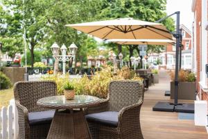 博尔库姆Hotel Haus am Park的庭院配有桌椅和遮阳伞。