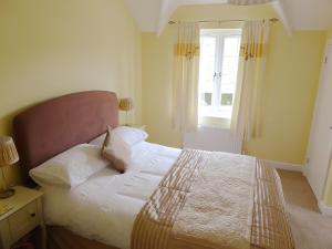 韦茅斯Pump Cottage的一间卧室配有一张带白色床单的床和一扇窗户。