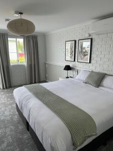 土乌巴三叶草酒店的卧室设有一张大白色床和两个窗户