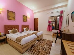 阿格拉The Hideout Agra - Boutique Homestay near Taj的配有粉红色墙壁的客房内的两张床