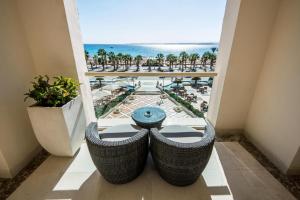 赫尔格达KaiSol Romance Resort Sahl Hasheesh - Adults Only的阳台配有桌子,享有海景。