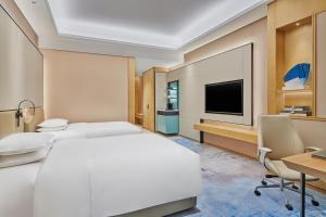 苏州苏州吴中希尔顿逸林酒店的酒店客房设有一张床、一张书桌和一台电视机。
