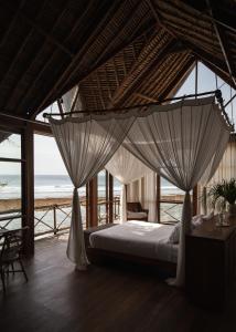 乌鲁瓦图Uluwatu Surf Shack的一间卧室配有带蚊帐的床铺,享有海景。