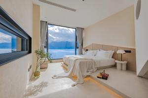 大理大理無双晴野·海景度假酒店（洱海店）的一间卧室设有一张大床和一个大窗户