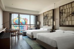 昌平北京乐多港万豪酒店的酒店客房带两张床和一张桌子以及椅子。