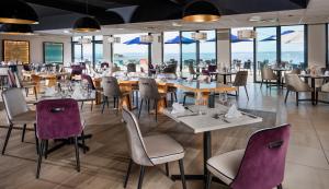 杜瓦讷内Hôtel Valdys Thalasso & Spa - la Baie的餐厅设有桌椅和窗户。