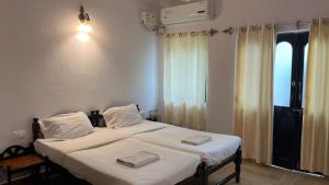 波戈马洛La Petite Guest House的一间卧室设有两张带白色床单的床和窗户。