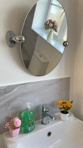 马斯顿格林Stylish 4beds home, perfect for Company contractors and family stays - NEC, Airport, HS2, Resort World的浴室水槽内装有镜子和鲜花