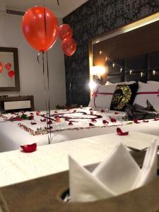 沃季赫Taj Al-Wajh Hotel的一间卧室配有一张红色气球和玫瑰床