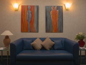 埃森Hotel Haus Gimken的客厅里一张蓝色的沙发,上面有三幅画