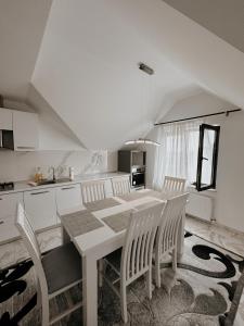 Vicovu de JosCazare Vicoveancaa的白色的厨房配有餐桌和椅子