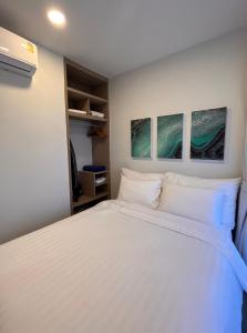 他朗2 br Laguna, SkyPark, Bang Tao的卧室配有一张白色床,墙上挂有三幅画作