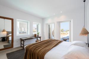 莫罗斯帕罗Exclusive Luxury Moca beachfront villa, Molos, Paros的卧室配有一张床、一张书桌和窗户。