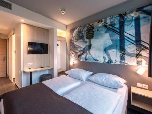 慕尼黑B&B Hotel München-Olympiapark的卧室配有一张床,墙上挂有绘画作品
