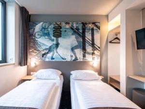 慕尼黑B&B Hotel München-Olympiapark的两张位于墙上的带海报的房间的床铺