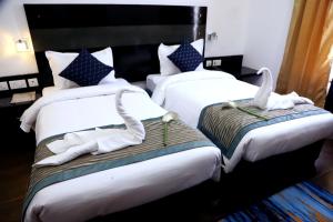 古尔冈Posh Classic的两张位于酒店客房的床,配有毛巾
