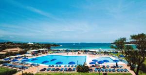 罗通多港Residence Hotel Nuraghe的一个带椅子和遮阳伞的大型游泳池,并享有海景。