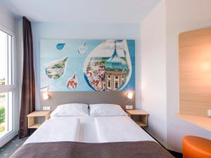 奥格斯堡B&B Hotel Augsburg-Nord的卧室配有一张床,墙上挂有绘画作品