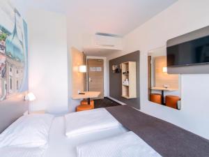 奥格斯堡B&B Hotel Augsburg-Nord的卧室配有白色的床和平面电视。