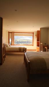 科伊艾科Coyhaique River Lodge的一间卧室设有两张床和大窗户