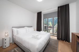 英格堡Swiss Hotel Apartments - Engelberg的卧室设有白色的床和大窗户