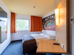 奥格斯堡B&B Hotel Augsburg-Süd的酒店客房配有一张床铺和一张桌子。