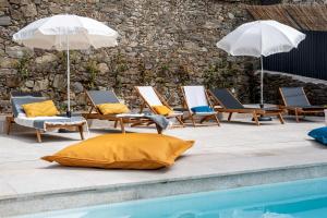 比索达雷加Feel Discovery Homes in Douro的一组躺椅和遮阳伞,位于游泳池旁