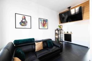 诺瓦拉Apartment Design 5 Stelle的客厅配有黑色真皮沙发和平面电视。