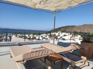 PírgosPyrgi Cretan Living & Spa的屋顶上配有2把躺椅和1把遮阳伞