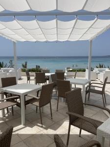 普佐伊杜Hotel da Cesare Maluentu的一个带桌椅的庭院和大海