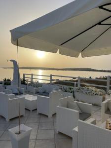 普佐伊杜Hotel da Cesare Maluentu的白色的庭院配有白色的椅子和遮阳伞