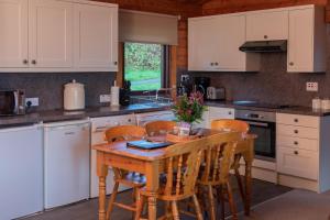 ArdvasarArmadale Castle Cabins的厨房配有白色橱柜和木桌及椅子