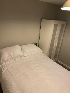ShephallCosy 1 Bed Home @Stevenage的一间卧室配有一张带白色床单和一盏灯的床。