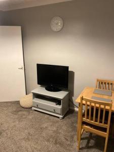 ShephallCosy 1 Bed Home @Stevenage的白色娱乐中心顶部的平面电视