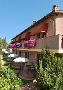 圣吉米纳诺Casa Vacanze con piscina a San Gimignano的一座建筑的侧面有雨伞和鲜花