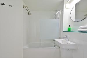 Saint-Aubin平衡骑士酒店的白色的浴室设有水槽和浴缸。
