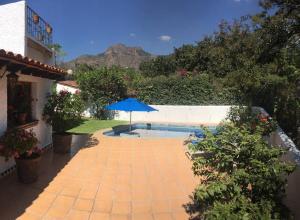 迪坡斯特兰Acogedora Villa con alberca climatizada en el centro de Tepoztlán的一个带遮阳伞和游泳池的庭院