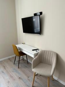 佩奇H30 Apartman的一张带椅子的白色书桌和墙上的电视