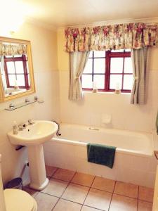 克拉伦斯Peebles Cottage的浴室配有盥洗盆、浴缸和盥洗盆
