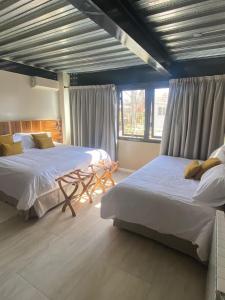 门多萨718 Rufino Petit Hotel的一间卧室设有两张床、一张桌子和窗户。