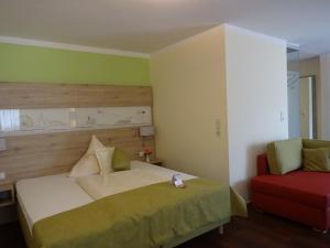 施特劳宾AKZENT Hotel Landgasthof Murrer的一间卧室配有一张床和一张红色椅子