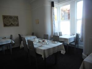 韦茅斯The George B&B的餐厅设有白色的桌椅和窗户。