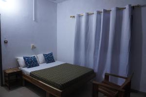 OuidahAu cœur de Ouidah的一间卧室配有一张带窗帘的床和一把椅子