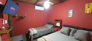 库穆鲁沙蒂巴Chalés Guigó-Cumuruxatiba的红色的房间,配有两张床和镜子