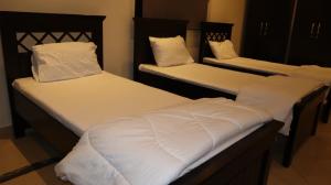 阿布扎比Budget Backpackers Hostel的客房内的两张单人床和白色床单
