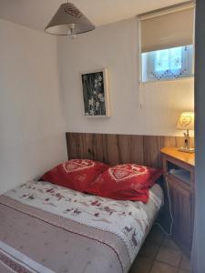 莱鲁斯Le Flocon, Superbe Cocon Montagnard en Rez de Jardin, Draps inclus et arrivée autonome的小卧室配有红色枕头的床