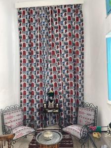 斯法克斯Dar Lella Hasna的一间设有两把椅子、一张桌子和窗帘的房间