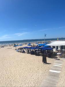 圣纳泽尔Villa des Cerisiers的海滩上设有蓝色的遮阳伞和椅子,还有海洋