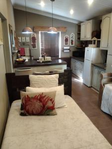 布隆方丹Rubyred Cottage的厨房配有白色橱柜和带枕头的桌子。