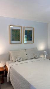 雅帕拉廷加比特恩吉尔帕亚酒店的卧室配有一张白色床,墙上挂有两张照片